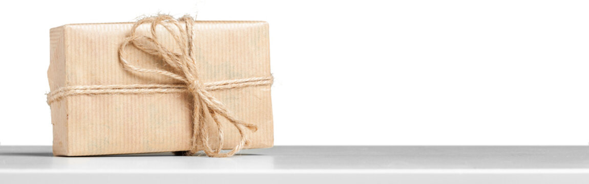 Gift wrapped package on a white shelf with twine and simple paper covering