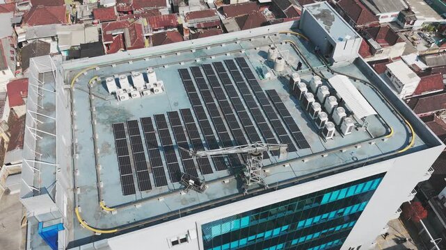 Aerial view of solar panels and HVAC units installed on a modern building rooftop in Malang, East Java, Indonesia.