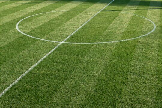 White center circle and halfway line on a striped green football pitch