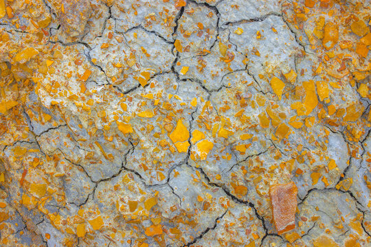 Aerial view of Karynzharyk salt flats featuring cracked earth and vibrant orange mineral deposits in Karakiya District, Mangystau Region, Kazakhstan.