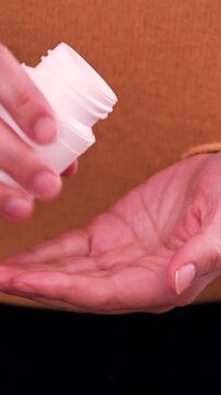 Person pouring yellow vitamin pills into hand