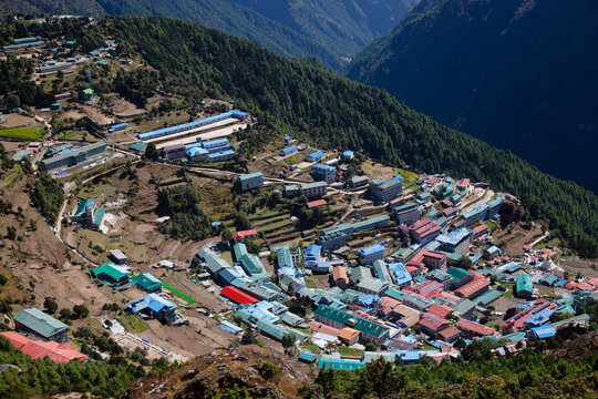 View of a mountain village with colorful buildings in a valley surrounded by hills and trees during daytime