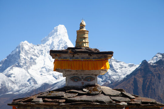 A view of a stupa with mountain backdrop in the Himalayas during daylight