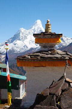 View of stupa with prayer flags and snow-capped mountain in the background during daytime in the Himalayas