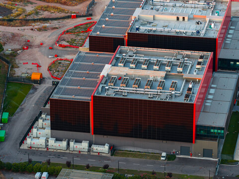 Aerial view of Aruba Hyper Cloud Datacenter IT4 featuring large industrial buildings with rooftop HVAC units and solar panels in Roma, Lazio, Italy.
