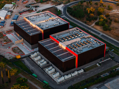 Aerial view of Aruba Hyper Cloud Datacenter IT4 featuring modern industrial buildings with rooftop HVAC units and solar panels surrounded by roads and landscape in Roma, Lazio, Italy.