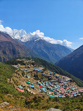 Mountains surround a small village in Nepal with colorful houses under a clear blue sky during the day