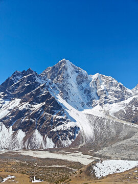 Snow-covered mountain peaks rise against a bright blue sky in a remote location during daytime