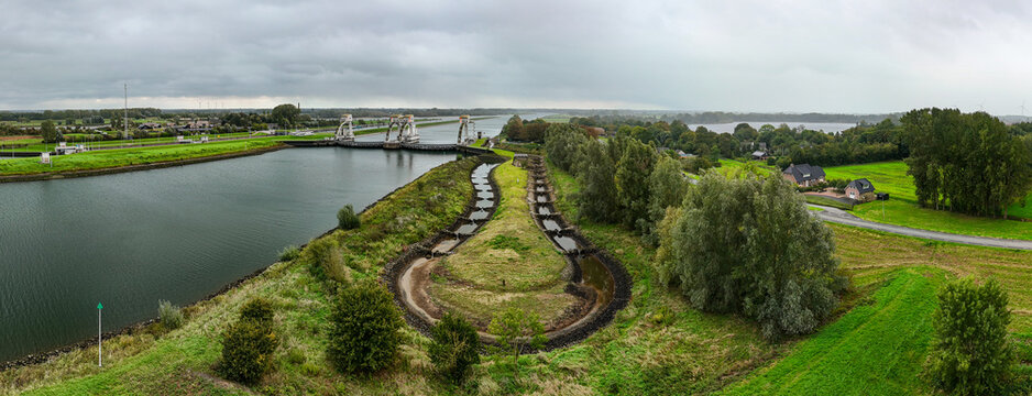 Aerial view of Sluis- en stuwcomplex Hagestein on the Lek river, featuring the weir and lock complex, green fields, trees, anda fish ladder, Hagestein, Utrecht, Netherlands.