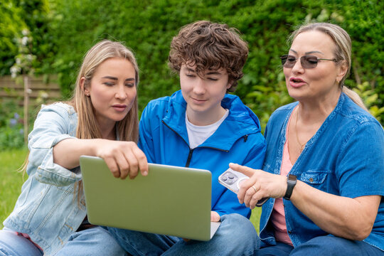 Group of three people using laptop in backyard during daytime