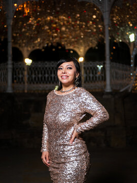 Woman in Elegant Dress Posing at a Festive Christmas Gazebo at Night