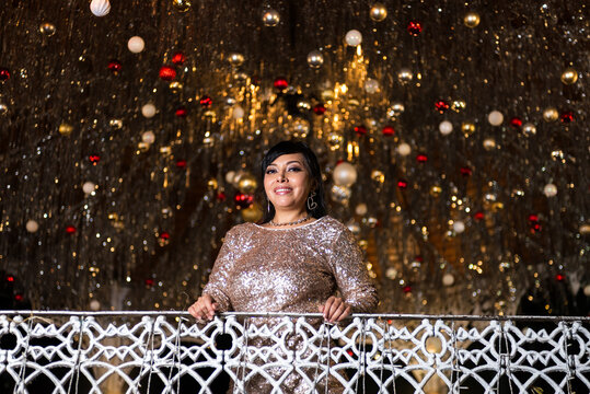 Woman in Elegant Dress Posing at a Festive Christmas Gazebo at Night