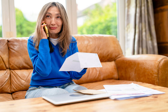 Woman talking on the phone while holding a letter in a cozy living room setting
