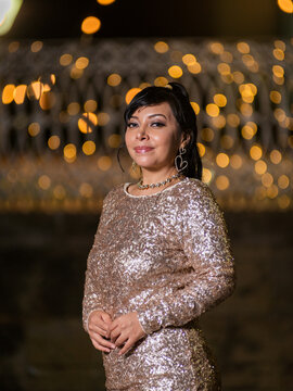 Woman in Elegant Dress Posing at a Festive Christmas Gazebo at Night