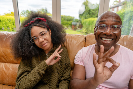 Family members making hand gestures while sitting together on a couch in a living room