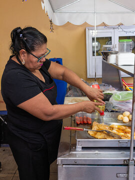 Woman Adding Oil to Tortillas on a Griddle at a Mexican Street Taqueria