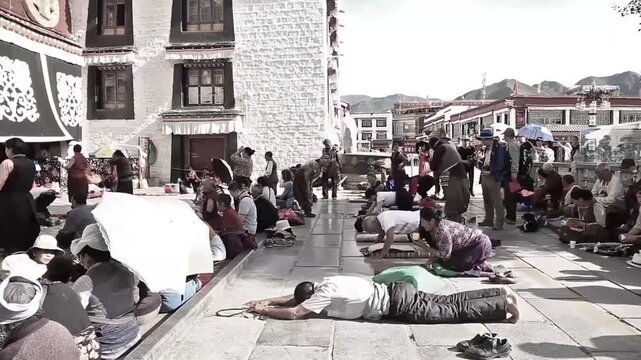 Tibetan Buddhist devotees prostrating and praying in front of Jokhang Temple courtyard in Lhasa