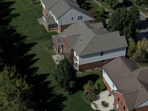 Aerial view of suburban houses with brick and siding exteriors, green lawns, and mature trees in a residential neighborhood in Mason, Ohio, United States.