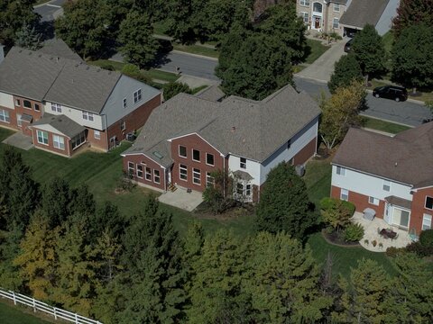 Aerial view of a suburban neighborhood featuring brick houses with shingled roofs, green lawns, and mature trees in Mason, Ohio, United States.