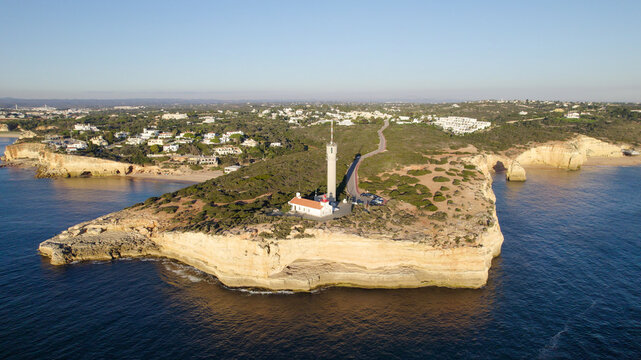 Aerial view of the Ponta do Altar Lighthouse situated on a rocky cliff overlooking the Atlantic Ocean in Ferragudo, Faro District, Portugal.