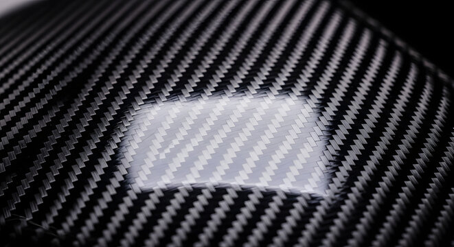 Glossy carbon fiber texture surface with light reflection close up background