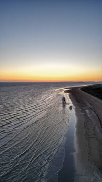 Aerial view of the iconic Burnham-on-Sea Low Lighthouse standing on the sandy beach during a vibrant sunset with calm waves gently lapping the shore in Burnham-on-Sea, England, United Kingdom.