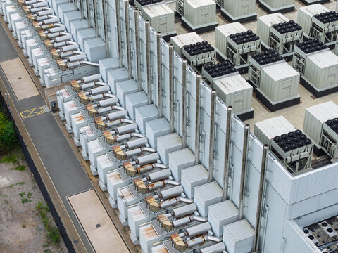 Aerial view of a data center rooftop featuring numerous industrial cooling units, ventilation pipes, and HVAC systems arranged in rows, United Kingdom.