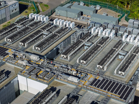 Aerial view of a large data center facility featuring rows of cooling units, industrial HVAC equipment, and solar panels on the roof in the United Kingdom.