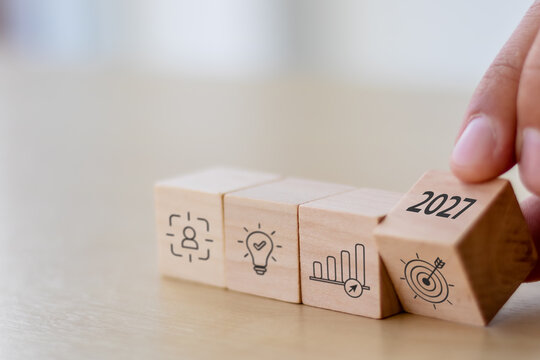 2027 Business Strategy. Future Goals and Growth Planning. Turning a 2027 wooden block beside icons of innovation, business growth and targets. Strategic planning, future vision and success.