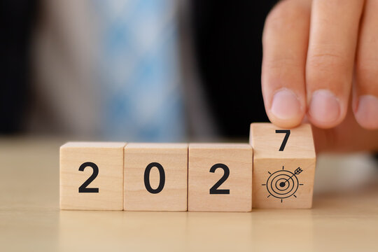 2027 Business Goals. Target Achievement, Strategic Planning. Placing a wooden 7 block with a bullseye target icon to complete 2027. Business goals, strategic planning, focus, ambition, future success.