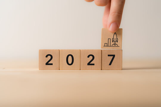 2027 Business Growth. Startup Success, Future Development. Placing a wooden block with a rocket and rising chart above 2027. Business growth, startup launch, innovation, strategic planning, success.