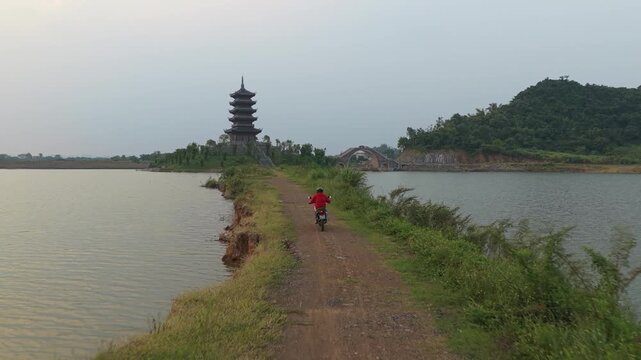 Person riding motorcycle towards pagoda zoe mascot in vietnam