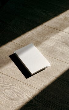 Blank white receipt folder resting on clean empty wooden surface in bright daylight