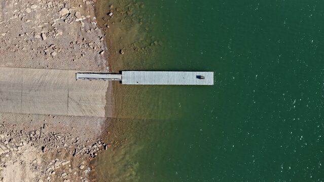 Aerial view of a boat ramp and dock extending into the calm green waters of Carter Lake Reservoir, with rocky shoreline and concrete ramp in Larimer County, Colorado, United States.