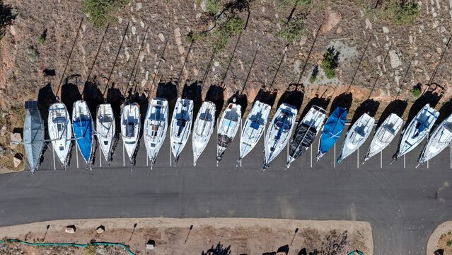 Aerial view of sailboats parked in a row on a paved lot near a rocky, tree-lined hillside at Carter Lake Reservoir, Larimer County, Colorado, United States.
