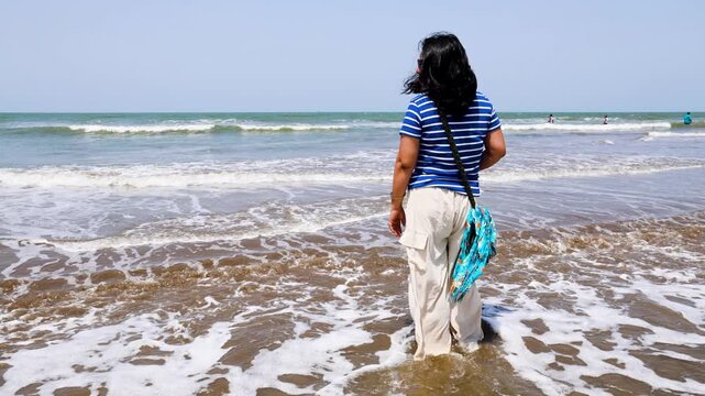 Female Tourist Enjoying Seaside Waves During A Relaxing Tropical Beach Holiday
