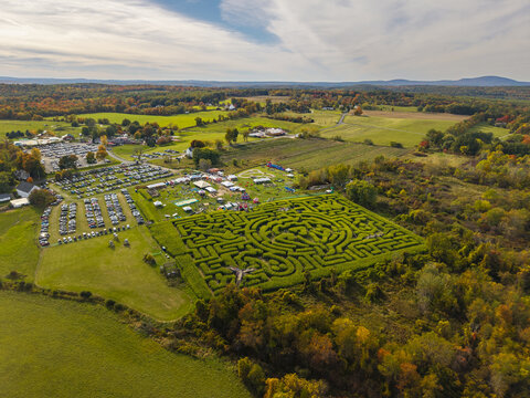 Aerial view of Davis Mega Maze surrounded by autumn foliage, farm fields, and a parking lot in Sterling, Massachusetts, United States.