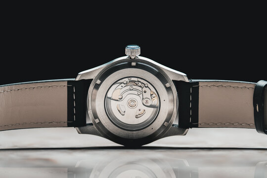 Swiss watch movement, back of analogue wristwatch showing mechanical cogs, leather strap