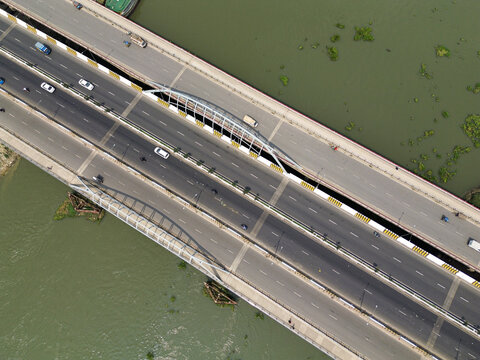 Aerial view of a modern bridge spanning a river with cars driving on the asphalt road in Dhaka, Dhaka Division, Bangladesh.