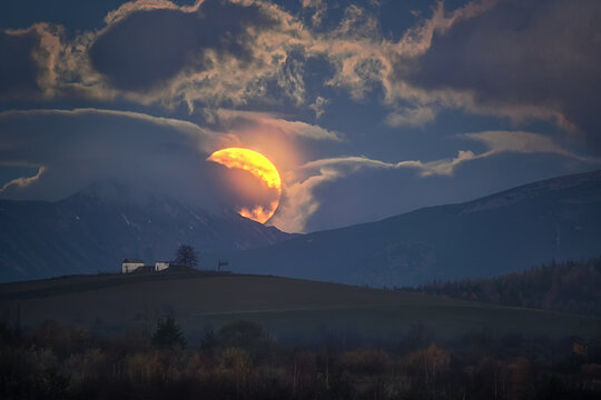 sun rising from behind the clouds in autumn