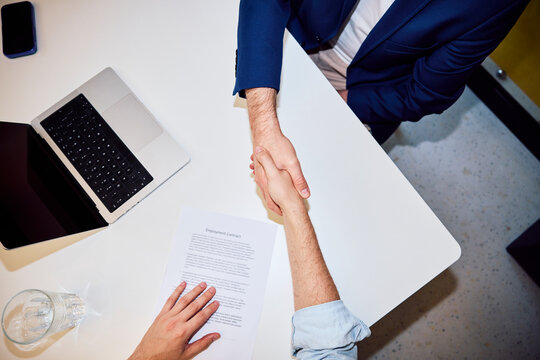 Businessman shaking hands over employment contract at office