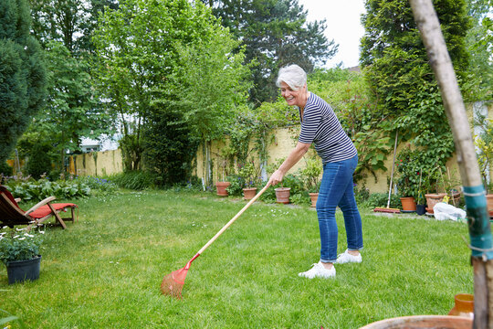 Woman raking on meadow in the garden
