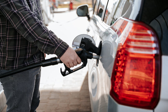 Hand holding fuel nozzle and refilling car at gas station