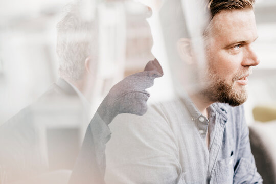 Mid adult man looking worried, second man giving advice