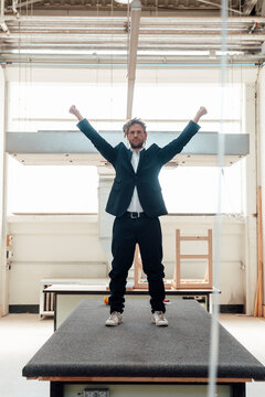 Man in suit stretches arms on table in carpentry workshop
