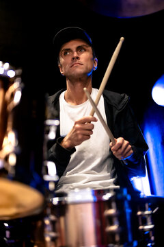 Focused man plays drums during rehearsal in a music studio