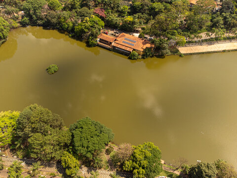 Aerial view of Parque Municipal Fabio da Silva Prado featuring the Lago Municipal, surrounded by lush green trees and a building with solar panels on its roof in Araras, Sao Paulo, Brazil.