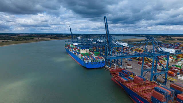 Aerial view of the Port of Felixstowe with container ships docked at the quay, colorful shipping containers, and massive gantry cranes in Felixstowe, England, United Kingdom.