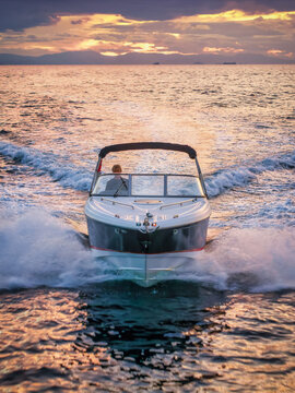 Front view of a motor speedboat cruising over the calm ocean during sunset time