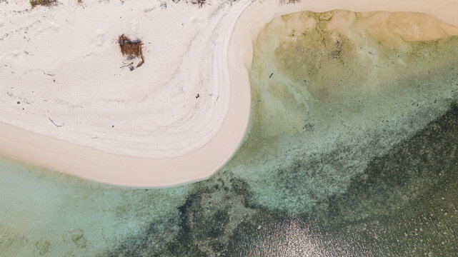 Aerial view of the pristine white sand beach and clear turquoise coral reef waters surrounding Cowo-Cowo Island, Wakatobi, Southeast Sulawesi, Indonesia.